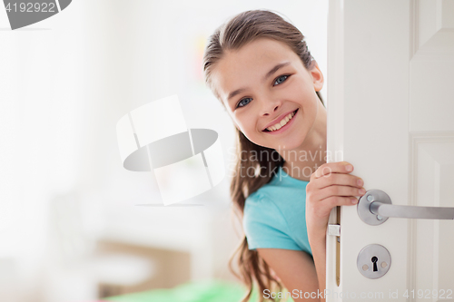 Image of happy smiling beautiful girl behind door at home