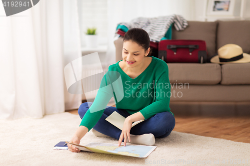 Image of woman with notebook and travel map at home