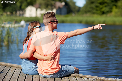 Image of happy couple pointing finger on summer river berth