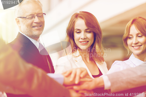 Image of business people putting hands on top in office