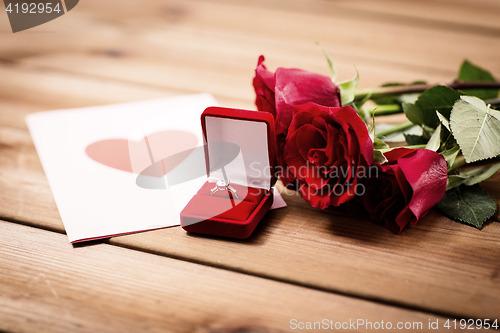 Image of close up of diamond ring, roses and greeting card