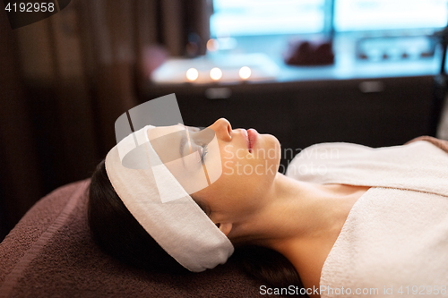 Image of young woman with headband lying in spa parlor