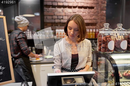 Image of woman or barmaid with cashbox at cafe