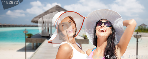 Image of smiling young women in hats on beach