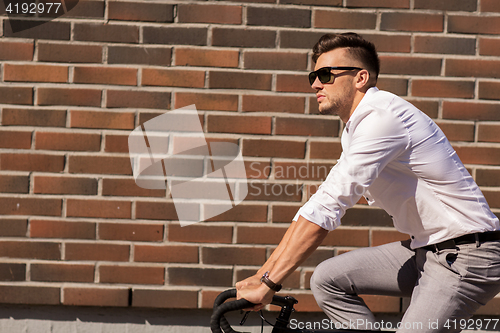 Image of young man riding bicycle on city street