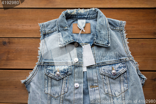 Image of close up of denim waistcoat with price tag on wood