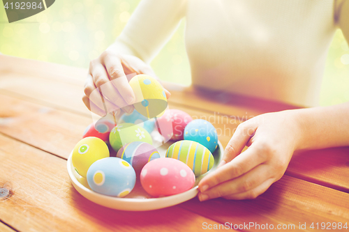 Image of close up of woman hands with colored easter eggs