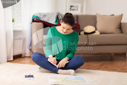 Image of woman with notebook and travel map at home