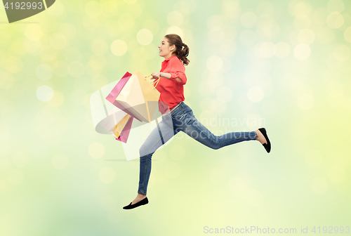 Image of smiling young woman with shopping bags jumping