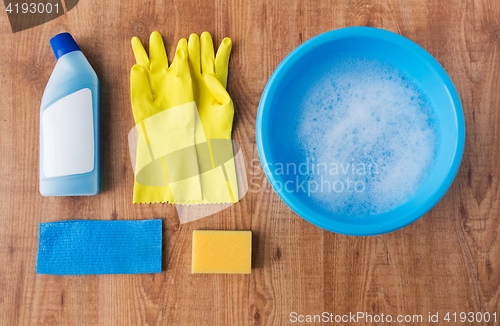 Image of basin with cleaning stuff on wooden background