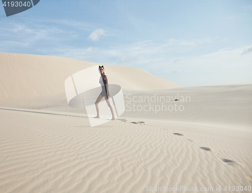 Image of young pretty woman in white sand dunes like a goddes of darkness