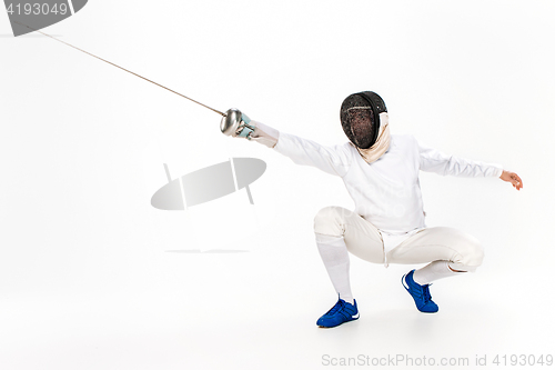 Image of Man wearing fencing suit practicing with sword against gray