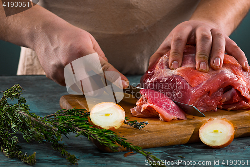 Image of Butcher cutting pork meat on kitchen