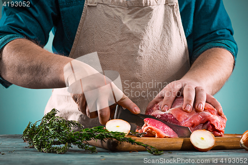 Image of Butcher cutting pork meat on kitchen