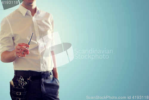 Image of close up of male stylist with scissors over blue