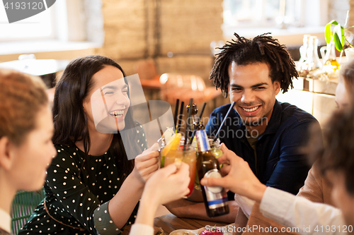 Image of happy friends clinking drinks at bar or cafe