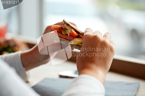 Image of woman eating salmon panini sandwich at restaurant