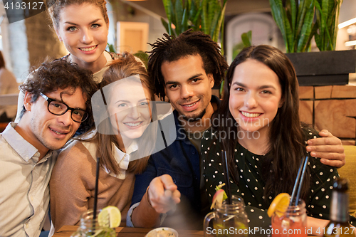 Image of friends taking selfie by smartphone at bar or cafe
