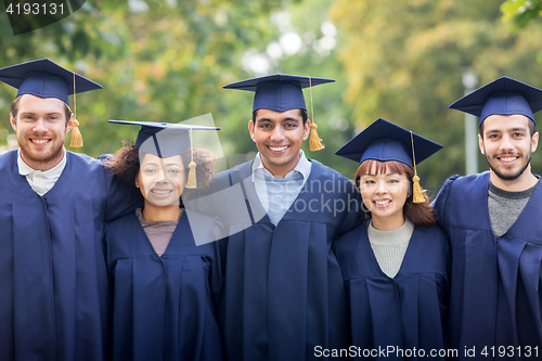 Image of happy students or bachelors in mortar boards