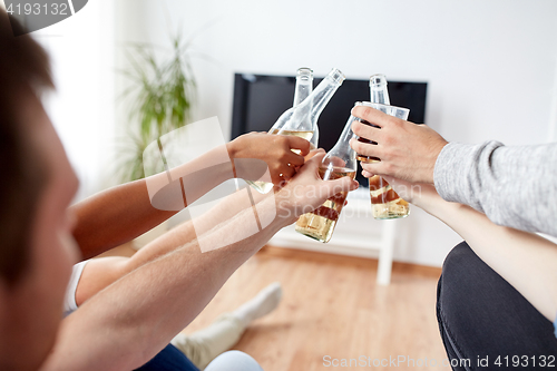 Image of friends clinking beer and watching tv at home