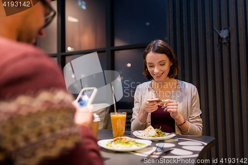 Image of happy couple with smartphones at vegan restaurant