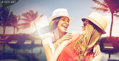 Image of smiling young women in hats on beach