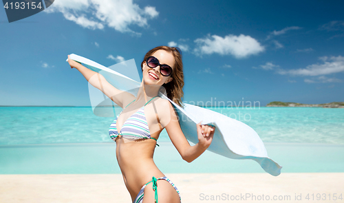 Image of woman in bikini and sunglasses with towel on beach