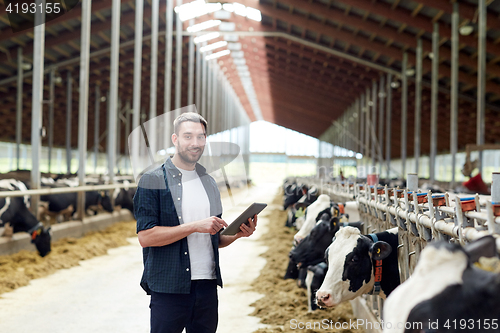 Image of young man with tablet pc and cows on dairy farm