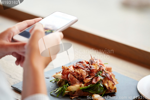 Image of hands with smartphone photographing food