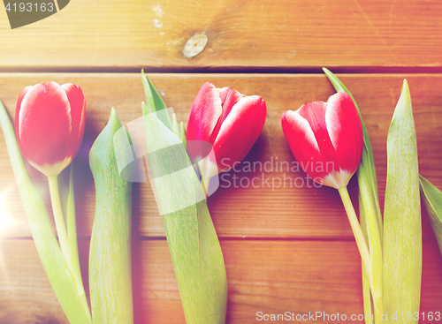 Image of close up of red tulip flowers on wooden table