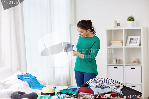 Image of woman with passport packing travel bag at home