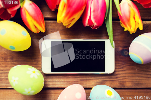 Image of close up of easter eggs, flowers and smartphone