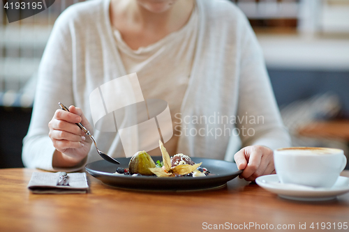 Image of woman eating ice cream dessert with coffee at cafe