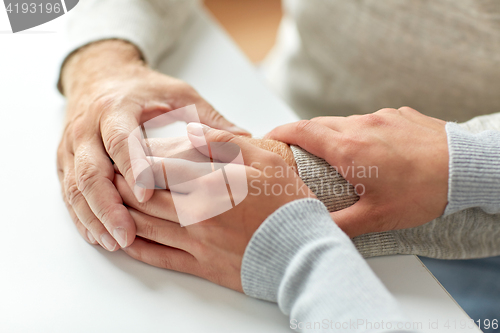 Image of close up of old man and young woman holding hands