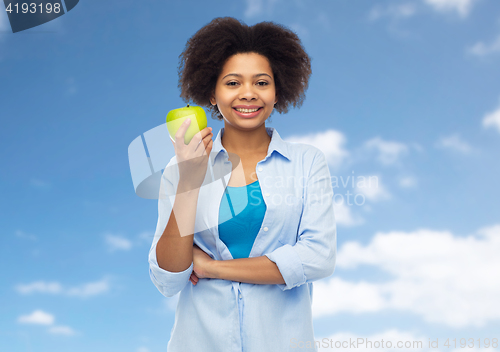 Image of happy african american woman with green apple