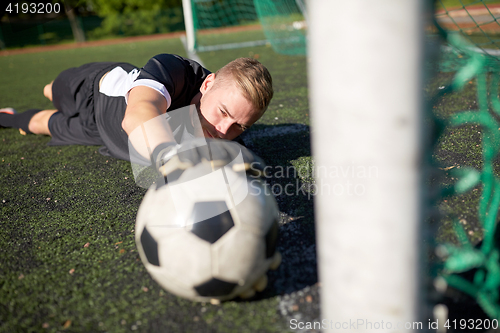 Image of goalkeeper with ball at football goal on field