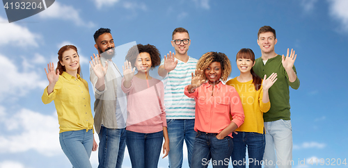 Image of international group of happy people waving hand