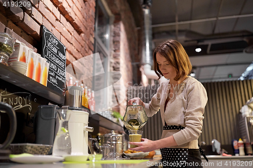 Image of woman or barmaid cooking smoothie at vegan cafe