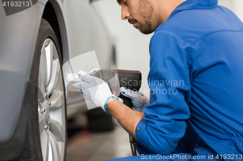 Image of mechanic with screwdriver changing car tire