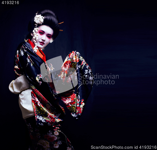 Image of young pretty real geisha in kimono with sakura and decoration