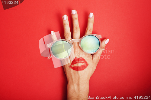 Image of woman hand holding sunglasses on bright background, cosmetic summer vacation concept