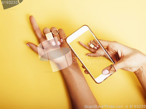 Image of womans hand taking picture of her new manicure with fashion jewellery on her phone, girls stuff concept