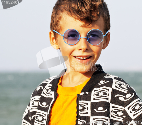 Image of cute little boy at seacoast in fashion clothers and blue glasses