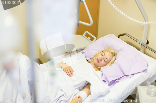 Image of Bedridden female patient recovering after surgery in hospital care.