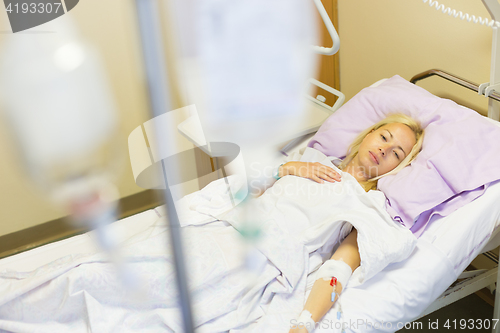 Image of Bedridden female patient recovering after surgery in hospital care.