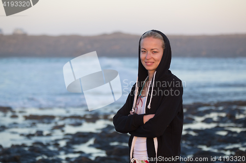 Image of Sporty woman on sandy beach at dusk.