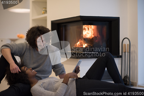 Image of multiethnic couple used tablet computer on the floor