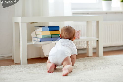 Image of little baby in diaper crawling on floor at home