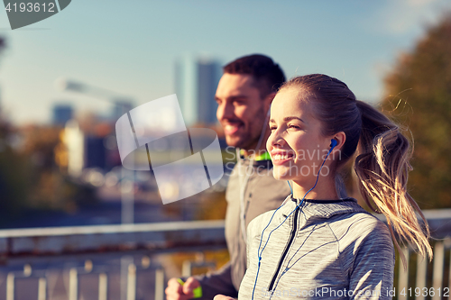 Image of happy couple with earphones running in city