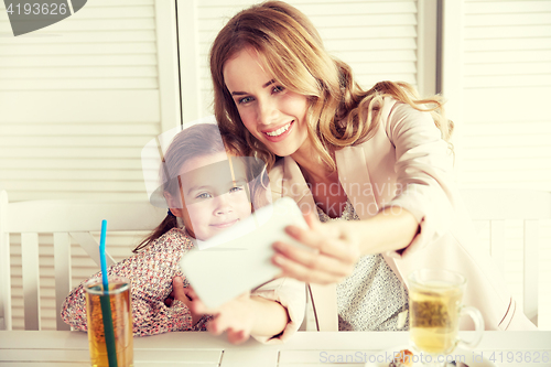 Image of happy family taking selfie at restaurant
